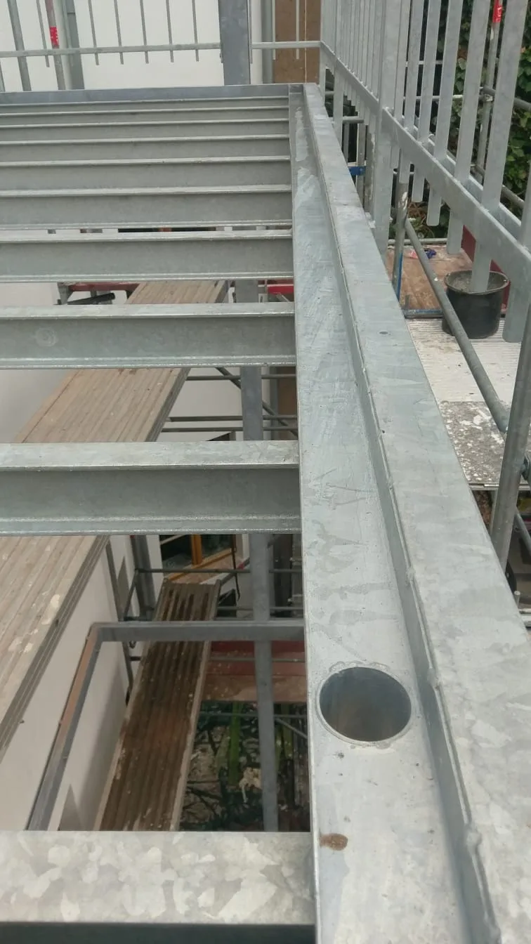 Feuerverzinkte Treppen- und Laufstegkonstruktion mit Gitterroststufen, Blick auf die Wange mit Abdeckkappe.