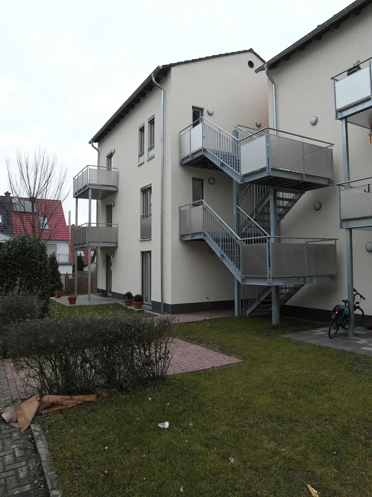 Feuerverzinkte Außentreppe über drei Ebenen mit Podesten und Lochblechbrüstung an der Rückseite eines Mehrfamilienhauses.